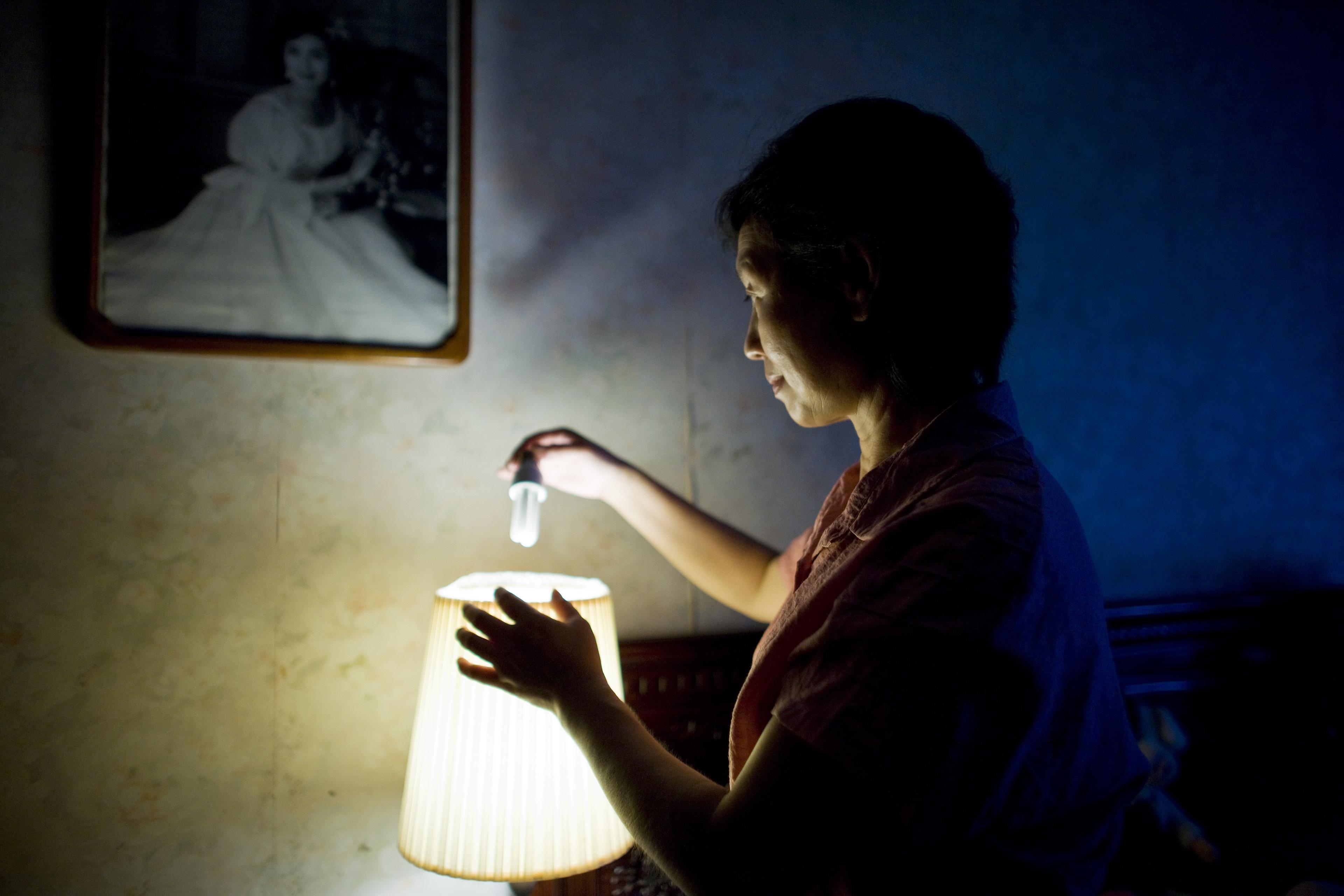 Mevrouw plaatst een een spaarzame gloeilamp in haar lamp