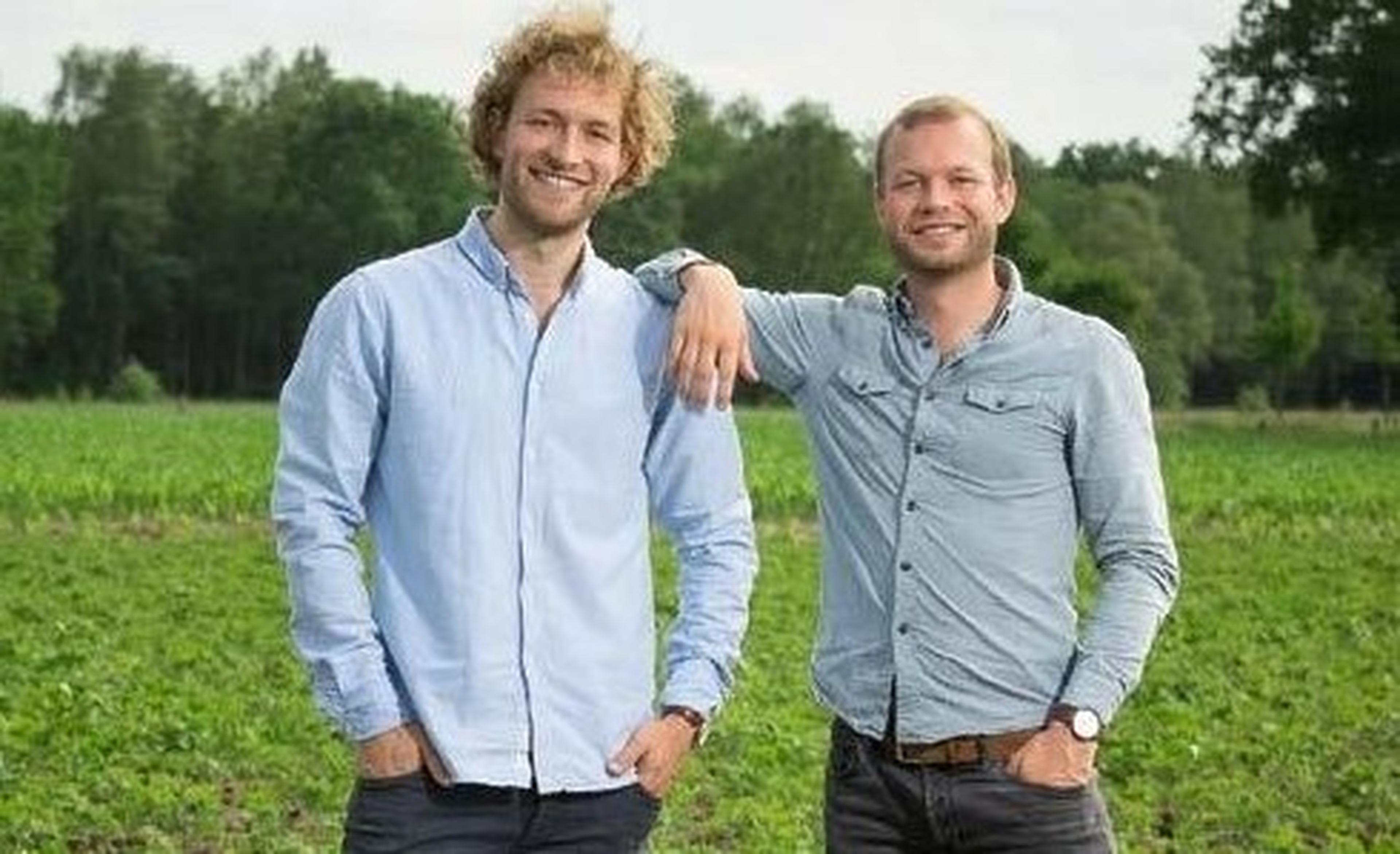 twee mannen en een hond staan in groen veld