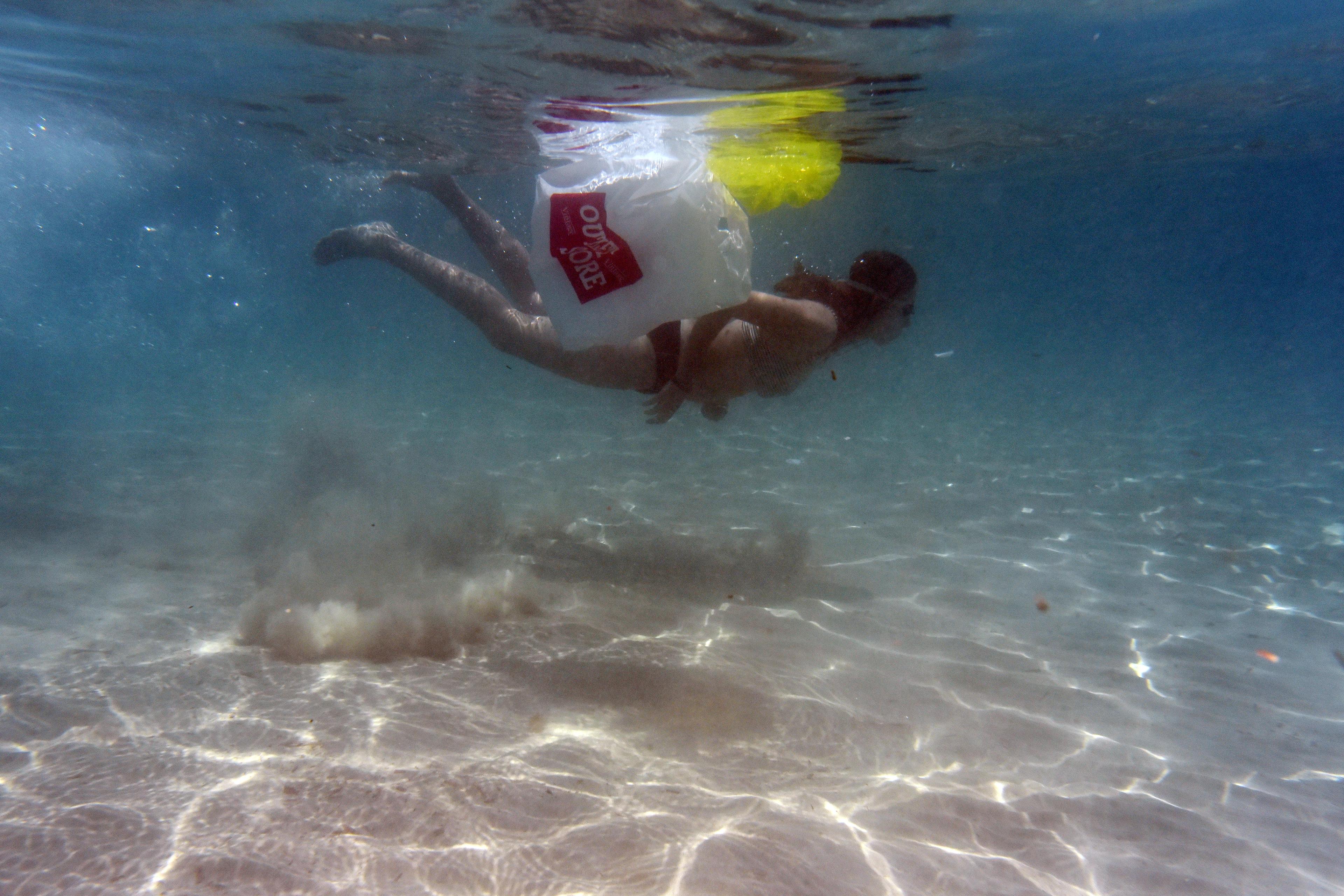 Plastic tasje drijft in de zee naast een zwemmer