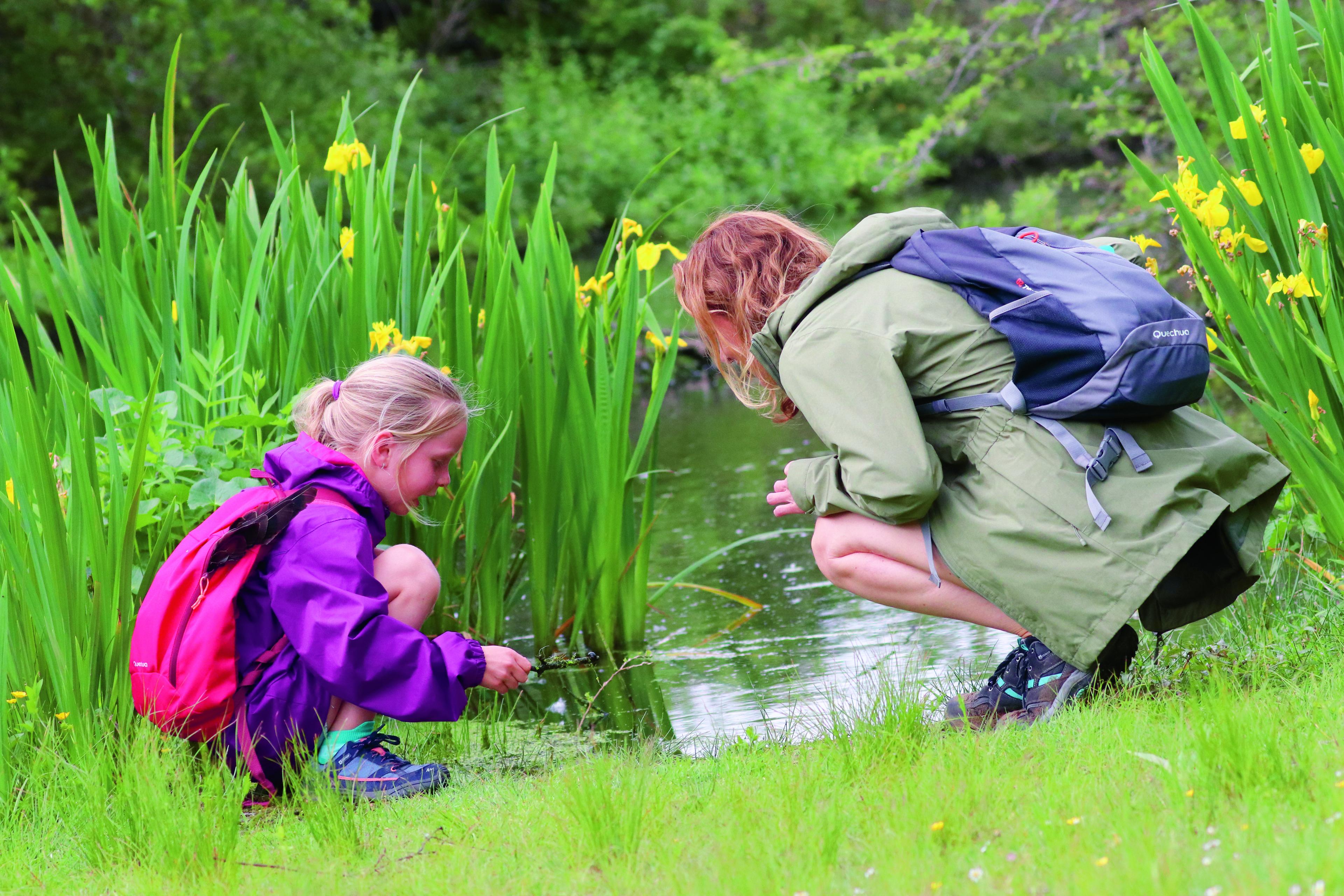 Vrouw en meisje gebukt aan de waterkant