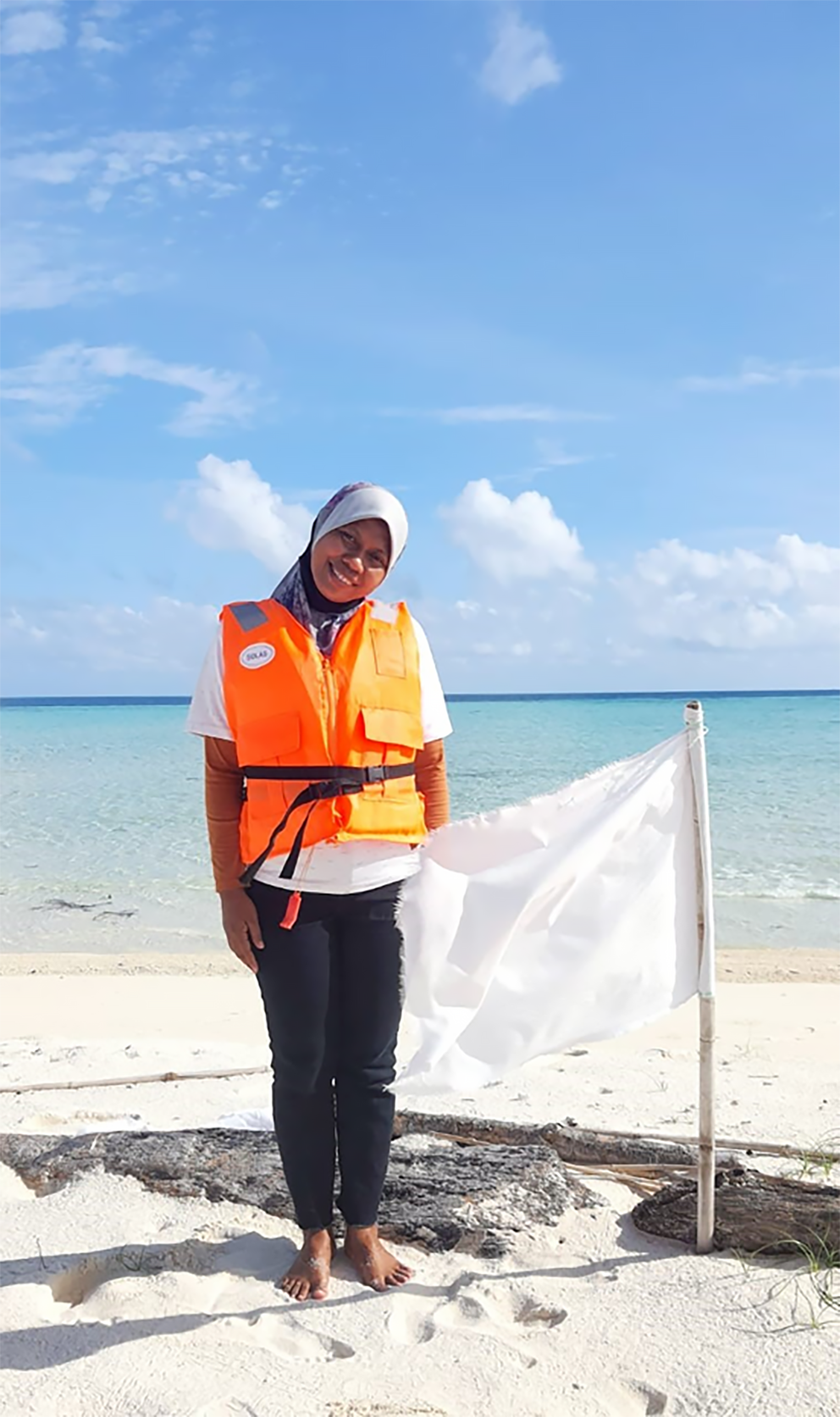 Intan Baljana binti Sapari, natuurbeschermer Koraaldriehoek, kijkt naar de camera, zee op de achtergrond