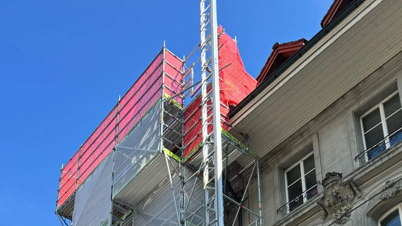 Fassadengerüst mit Baulift und rotem Schutznetz an einem Altstadthaus in Bern