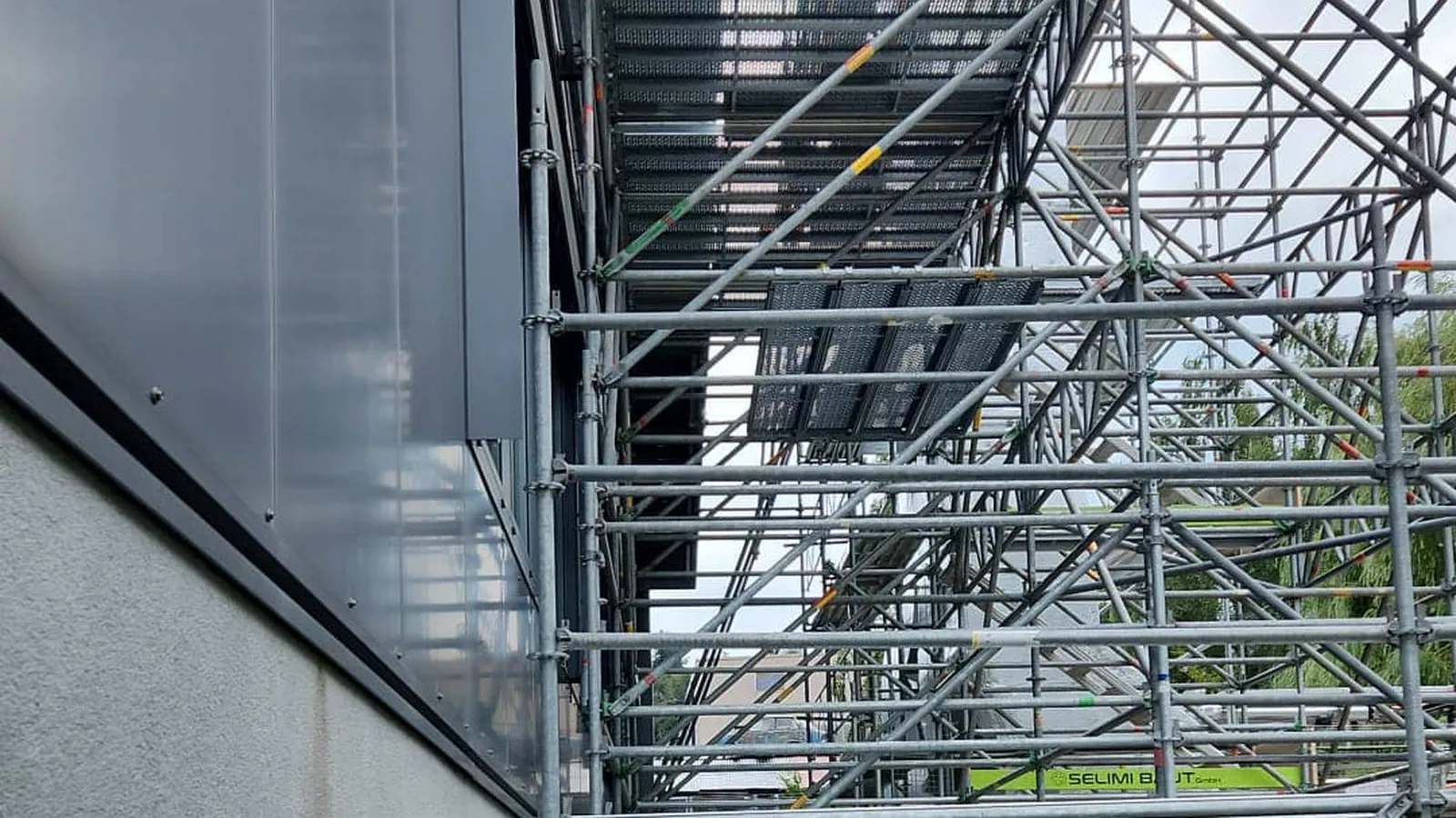 Treppenaufstieg aus Gerüst entlang einer Gebäudefassade auf einem Industrieareal