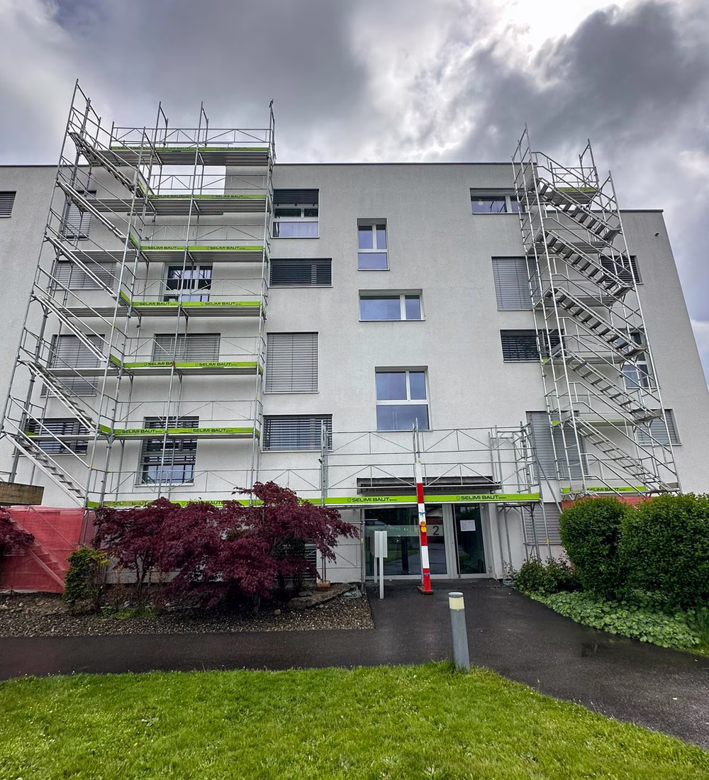 Mehrfamilienhaus mit Fassadengerüst, Treppenturm und Schutzdach über dem Hauseingang