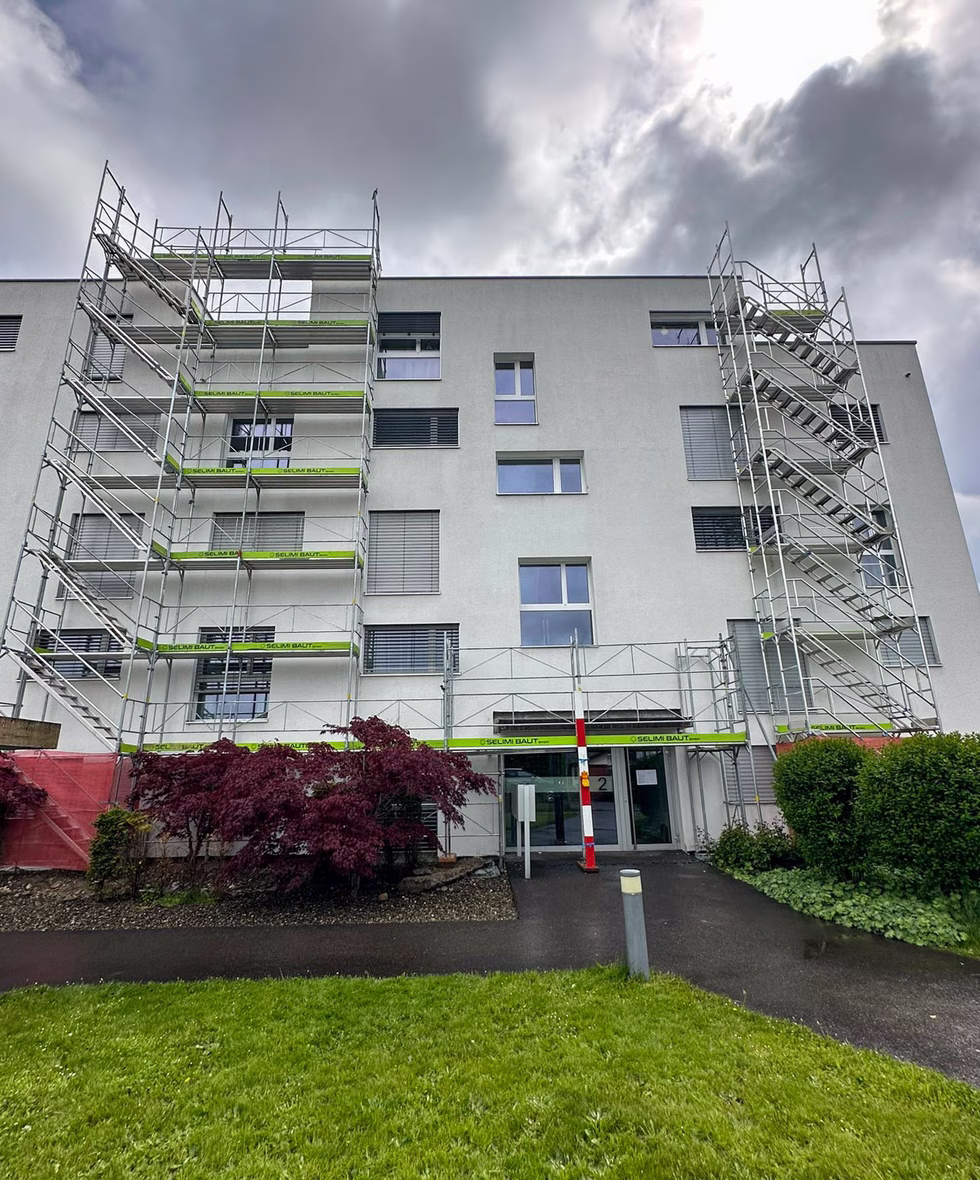 Fassadengerüst von zum Glück Gerüstbau an einem Mehrfamilienhaus – mit gebrandeten Belägen