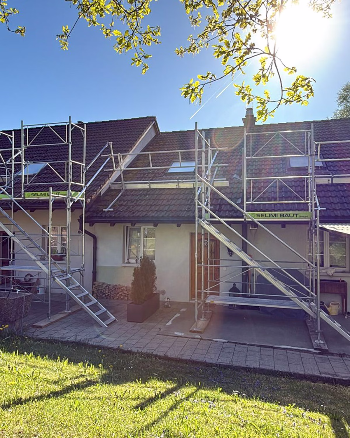 Eingerüstetes Einfamilienhaus mit Dachrandsicherung und Treppenaufstiegen