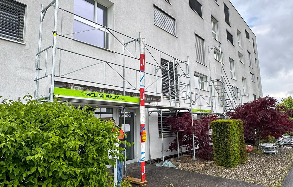Gerüst mit Schutzdach über dem Eingang eines bewohnten Mehrfamilienhauses