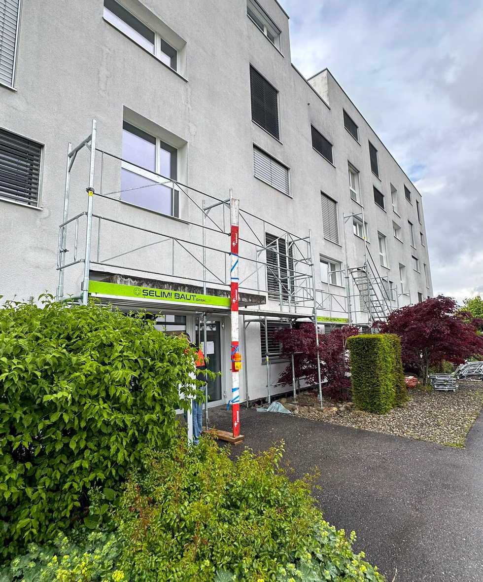 Fassadengerüst mit Schutzdach über dem Hauseingang eines Mehrfamilienhauses