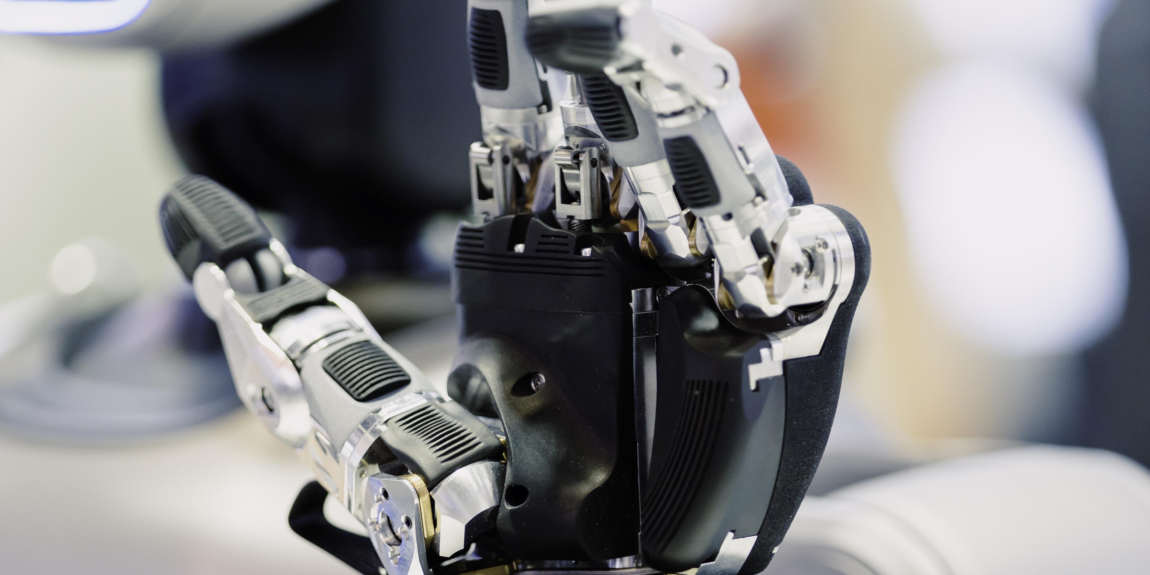 Close view of a humanoid robot hand mounted on an industrial arm.