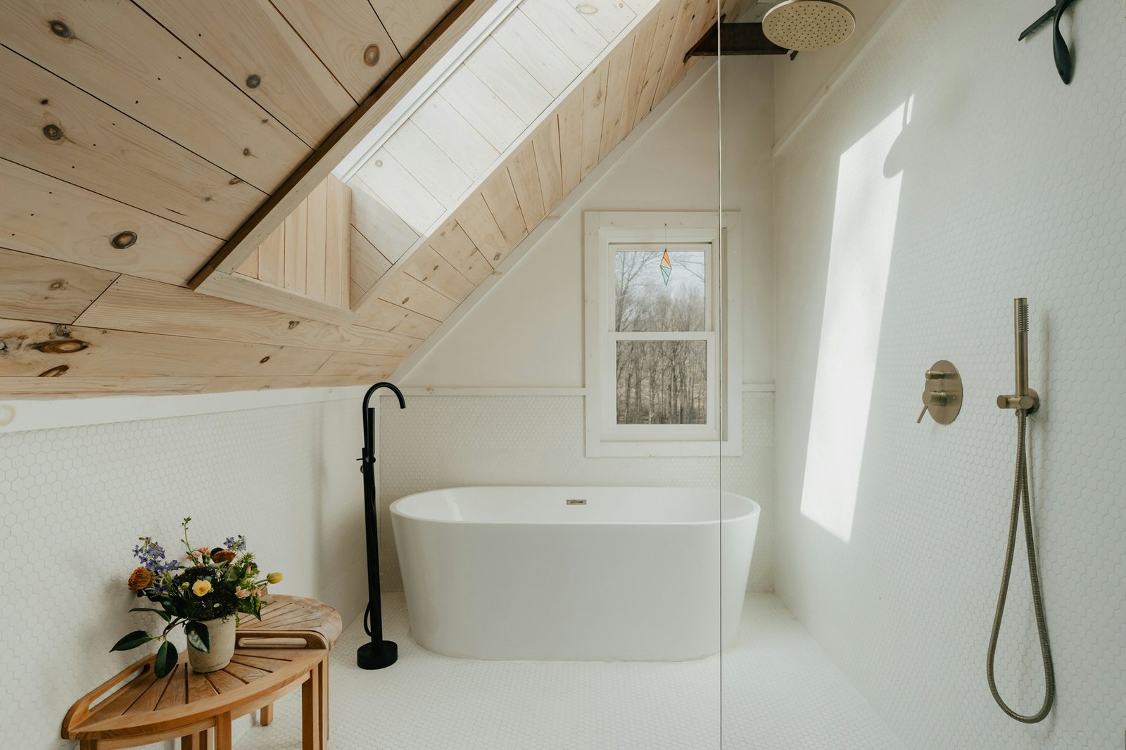 A bright bathroom with a freestanding tub under a timber ceiling.