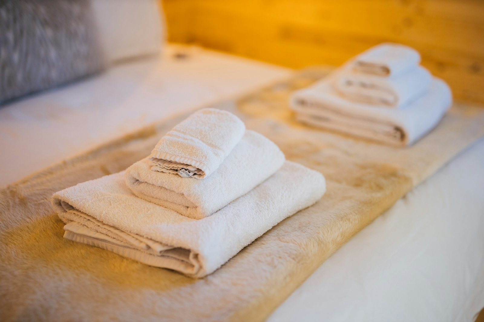 Folded white towels laid out on the bed.