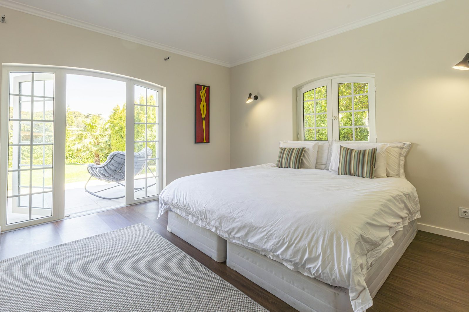 A bright bedroom with arched doors opening onto the garden.