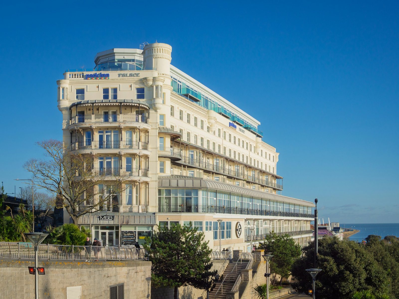 A grand white seaside hotel above the boulevard.
