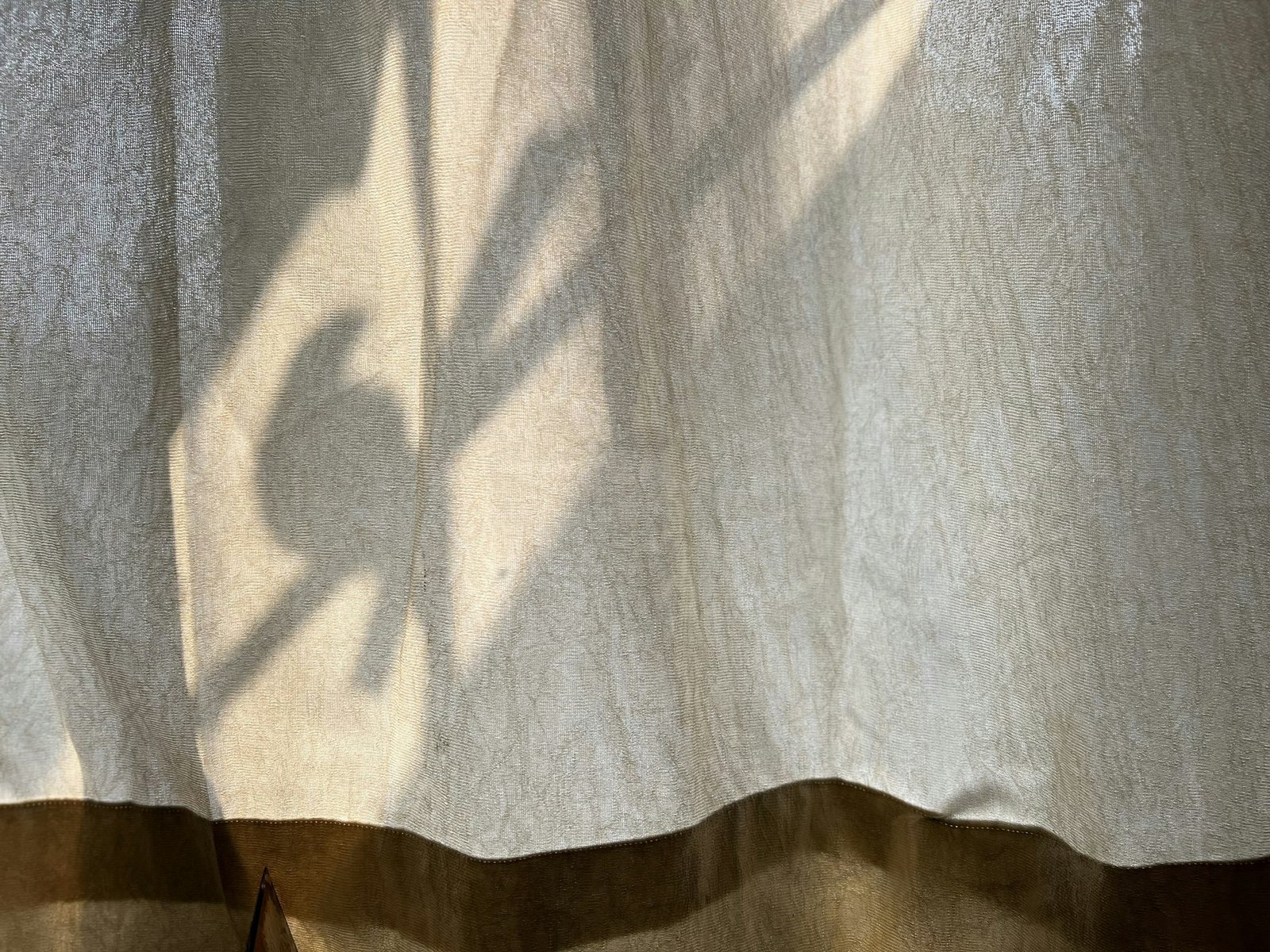 Plant shadows falling across a linen curtain.