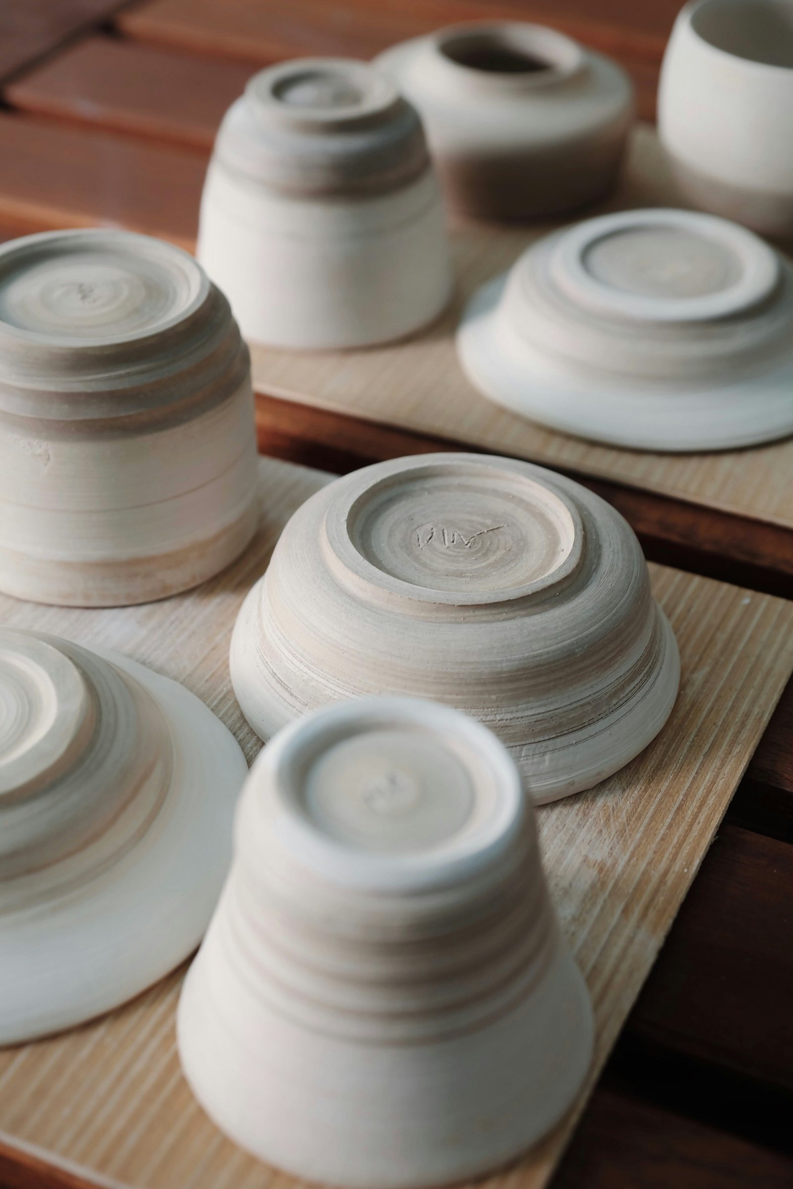 Unglazed ceramic bowls drying on wooden boards.