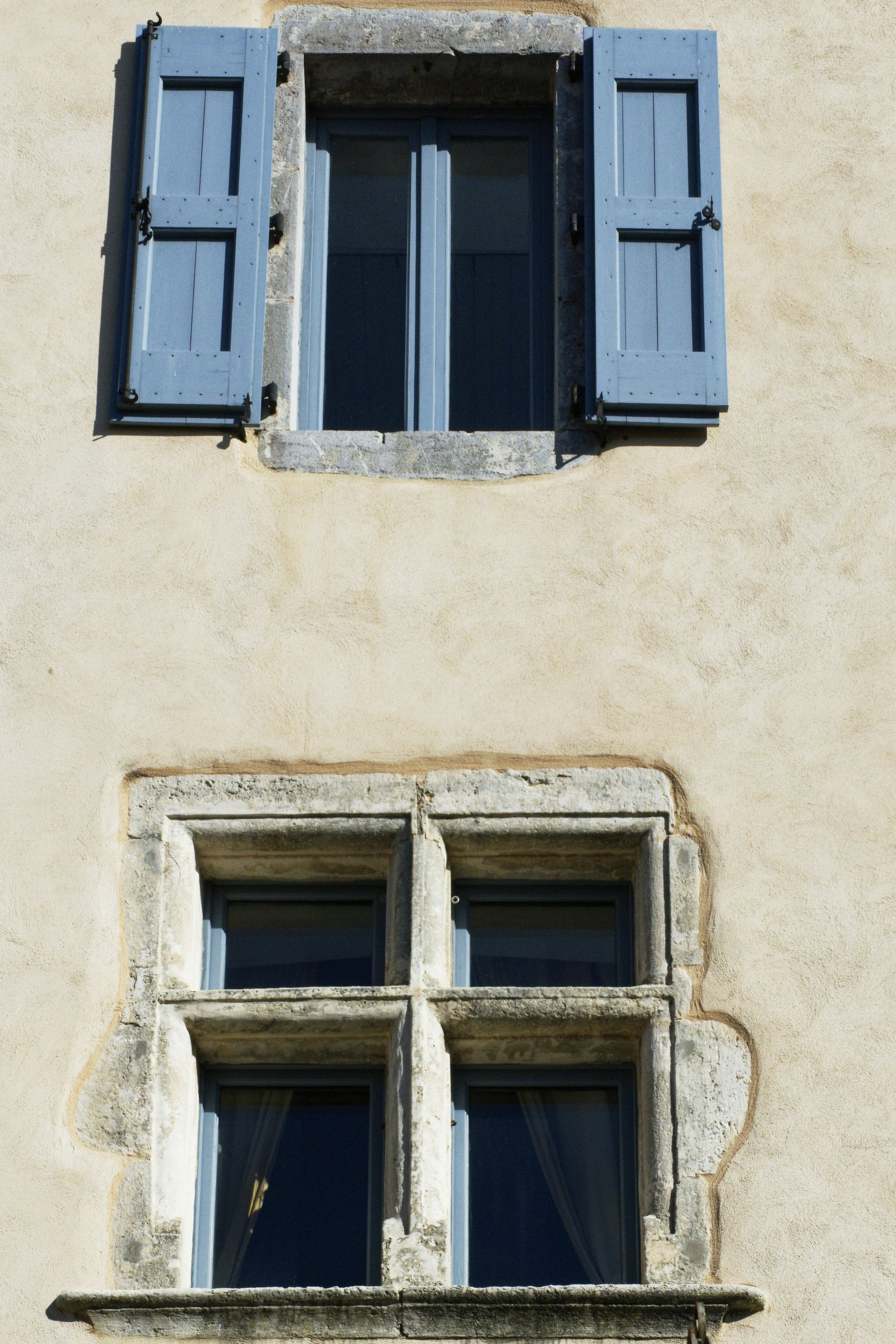 Blue-shuttered windows in a cream stucco wall.