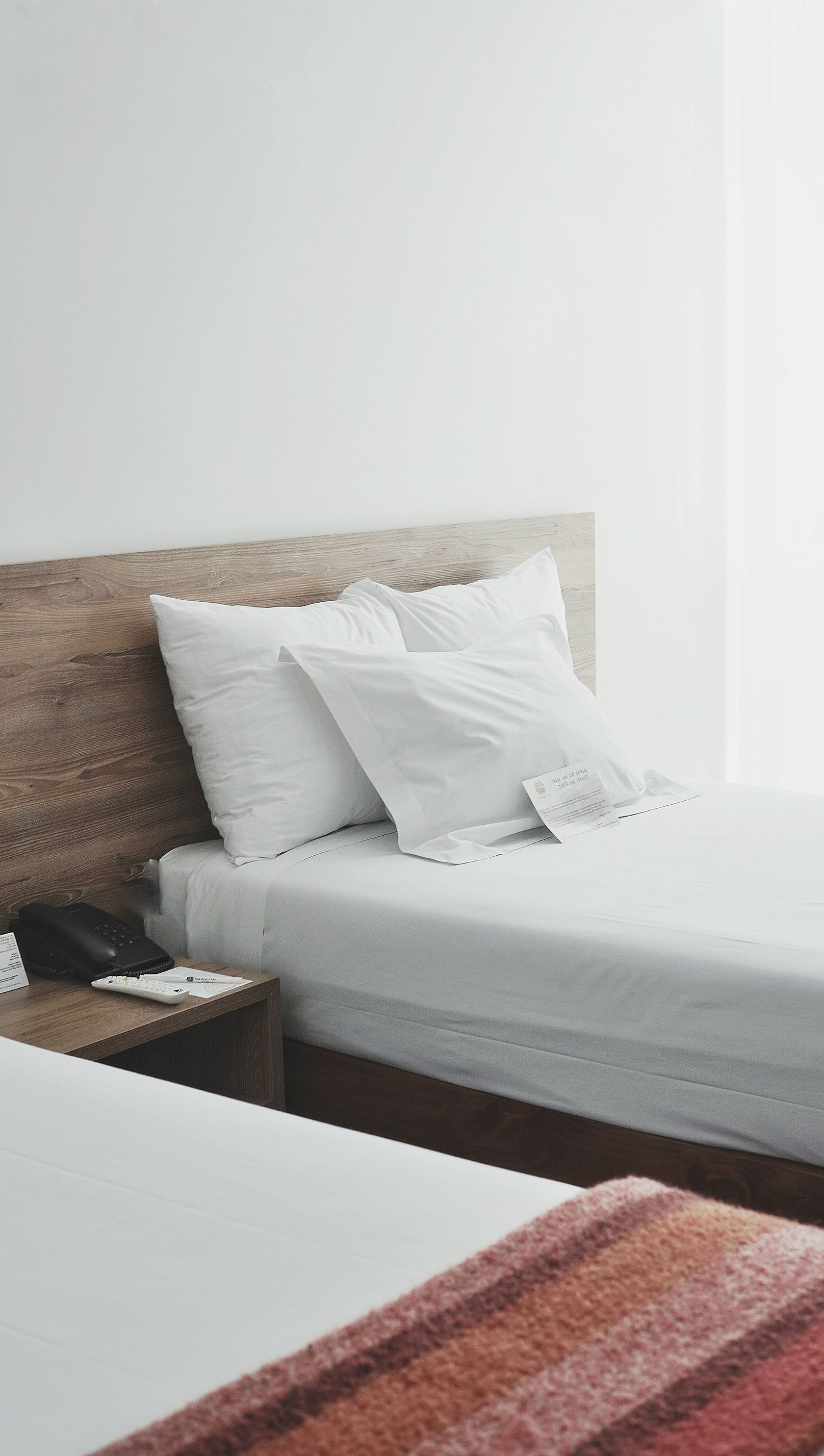 Crisp white bedding against a warm timber headboard in a compact room.