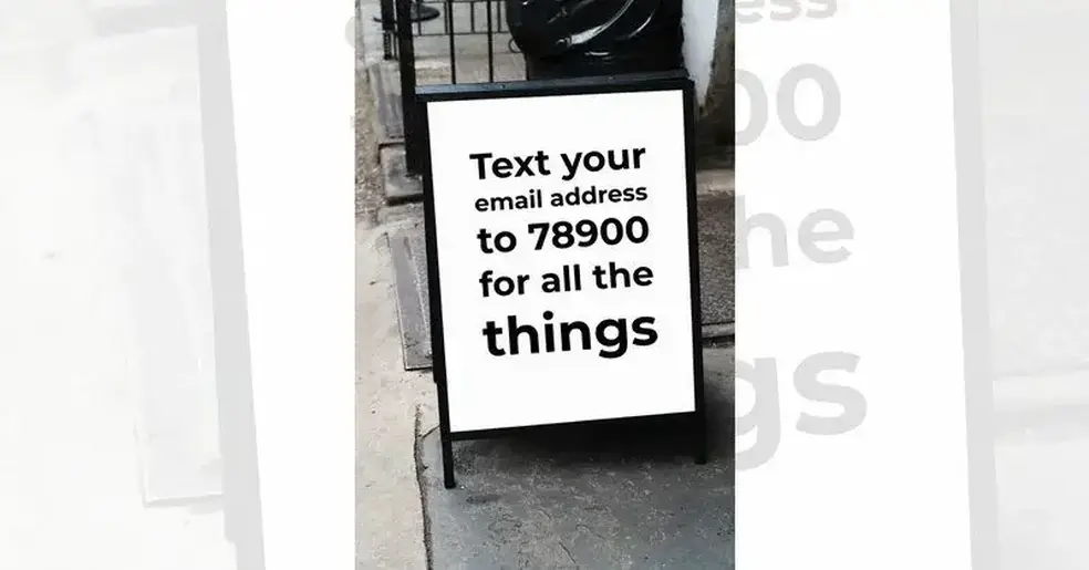 Outdoor sign with basic black on white message 'text your email address to 78900 for all the things'