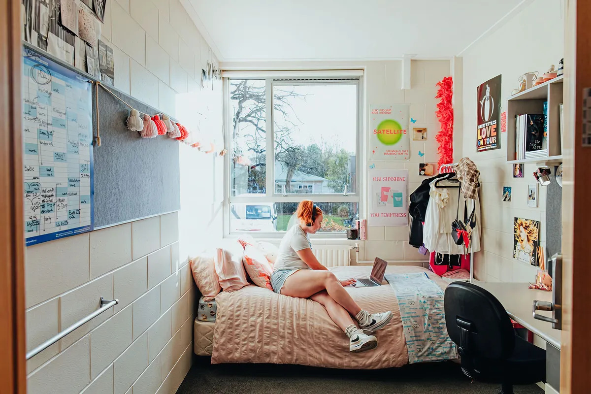 Student working on a laptop in her decorated study bedroom