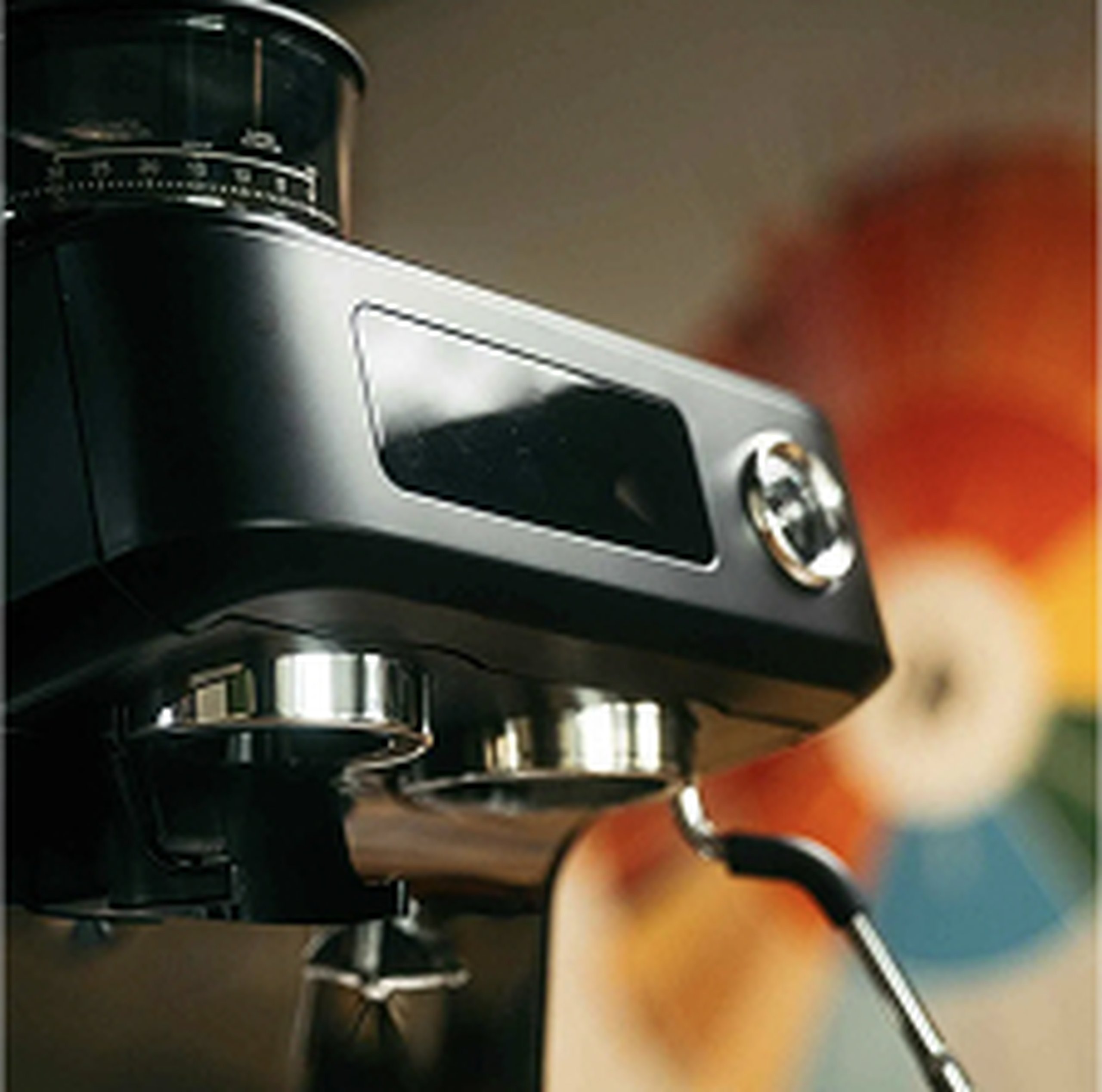 Black espresso machine with shiny metal components in focus, colorful blurred background creating a warm ambiance.