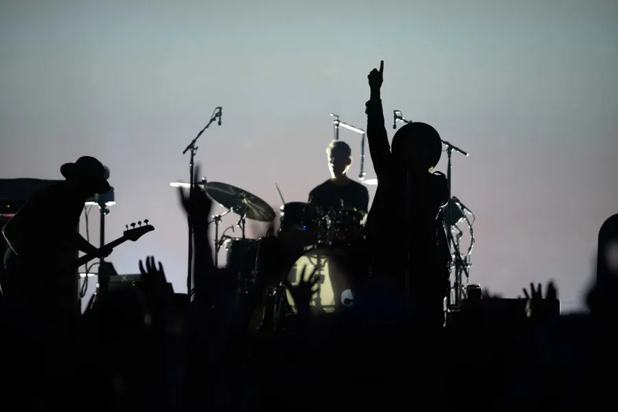 Band als silhouet tegen een lichte achtergrond, de zanger met geheven arm