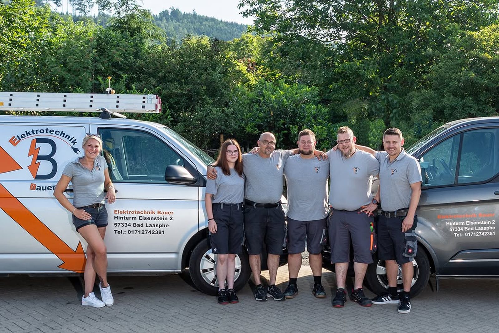Das Team von Elektrotechnik Bauer vor den Firmenwagen