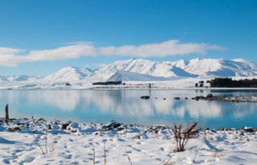 Snow-covered lake with mountain reflections under a clear blue sky