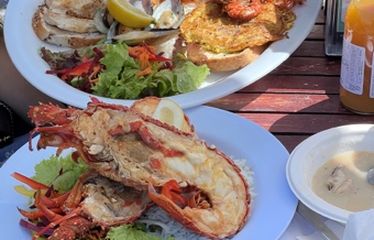 Plates of fresh seafood with salad and soup served at an outdoor restaurant