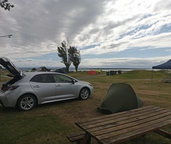 Silver car by the ocean with a signpost