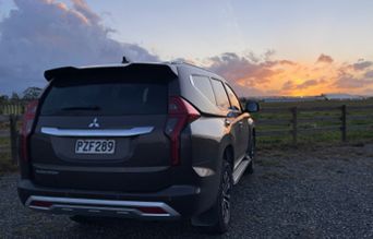 SUV parked at sunset near a rural fence