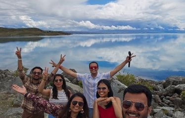 Group of friends taking a selfie by a clear lake with reflections of clouds