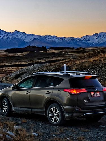Image of a Toyota Rav4 at dusk overlooking the lakes and mountains of the South Island