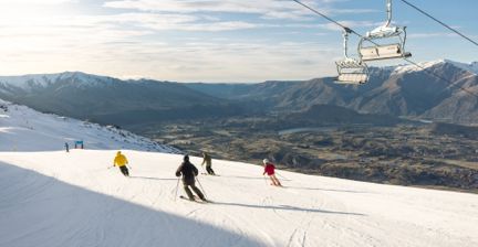 Skiers on a snowy slope with mountain views