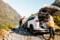 Person standing beside an open GO Rentals SUV trunk on a mountain road