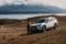 White GO Rentals SUV parked on a dry landscape with mountains and a lake in the background