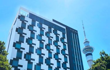 Sudima Auckland City hotel building with Sky Tower in the background
