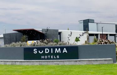 Sign and exterior of Sudima Christchurch Airport hotel with green lawn