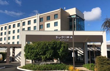 Exterior view of Sudima Auckland Airport hotel with trees and blue sky