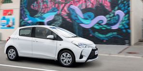 Image of a white Toyota Yaris hatchback parked beside a graffiti wall