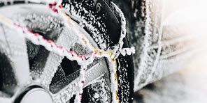 Image of snow chains fitted to the wheel of a rental car