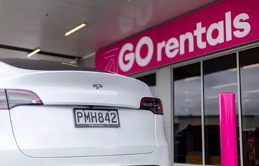 Rear view of a white Tesla Model Y parked at GO Rentals