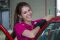 Image of a member of the GO Rentals team wearing a pink shirt smiling as she prepares a rental car for a customer