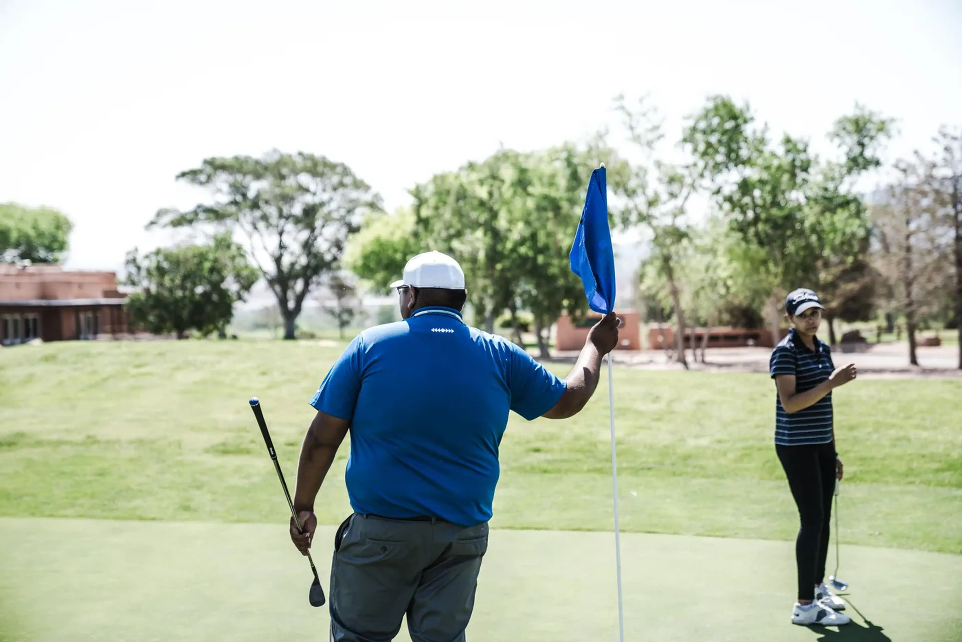 Two golfers at the flag on a green