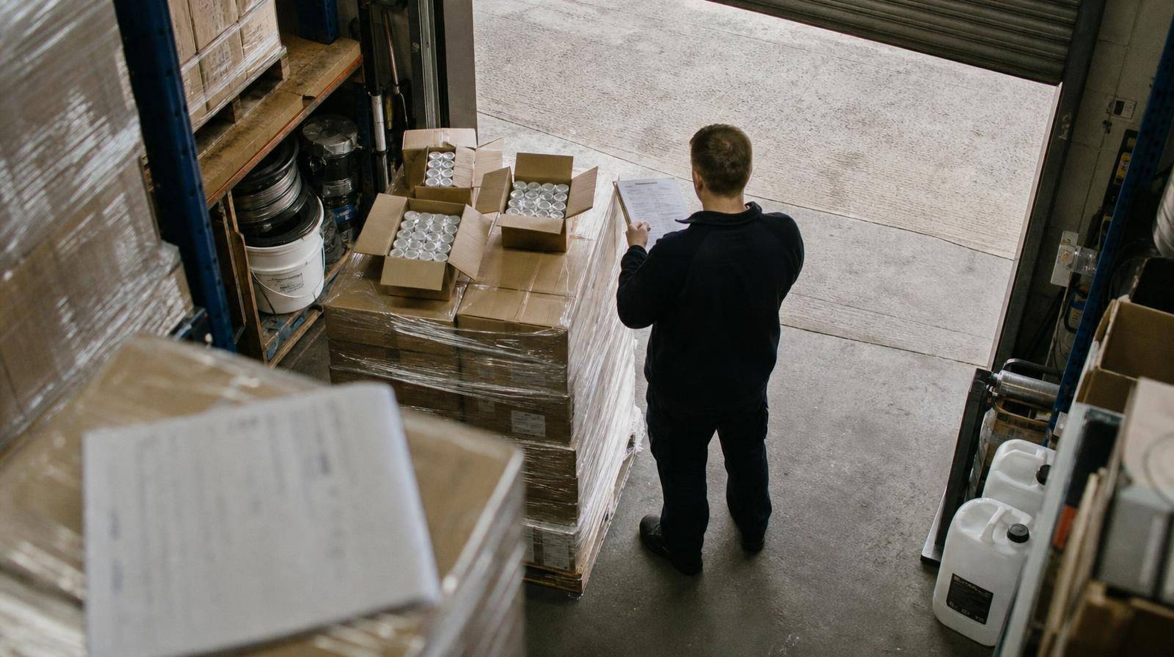 Cartons part-opened on a pallet at a goods-in door, receiver checking behind