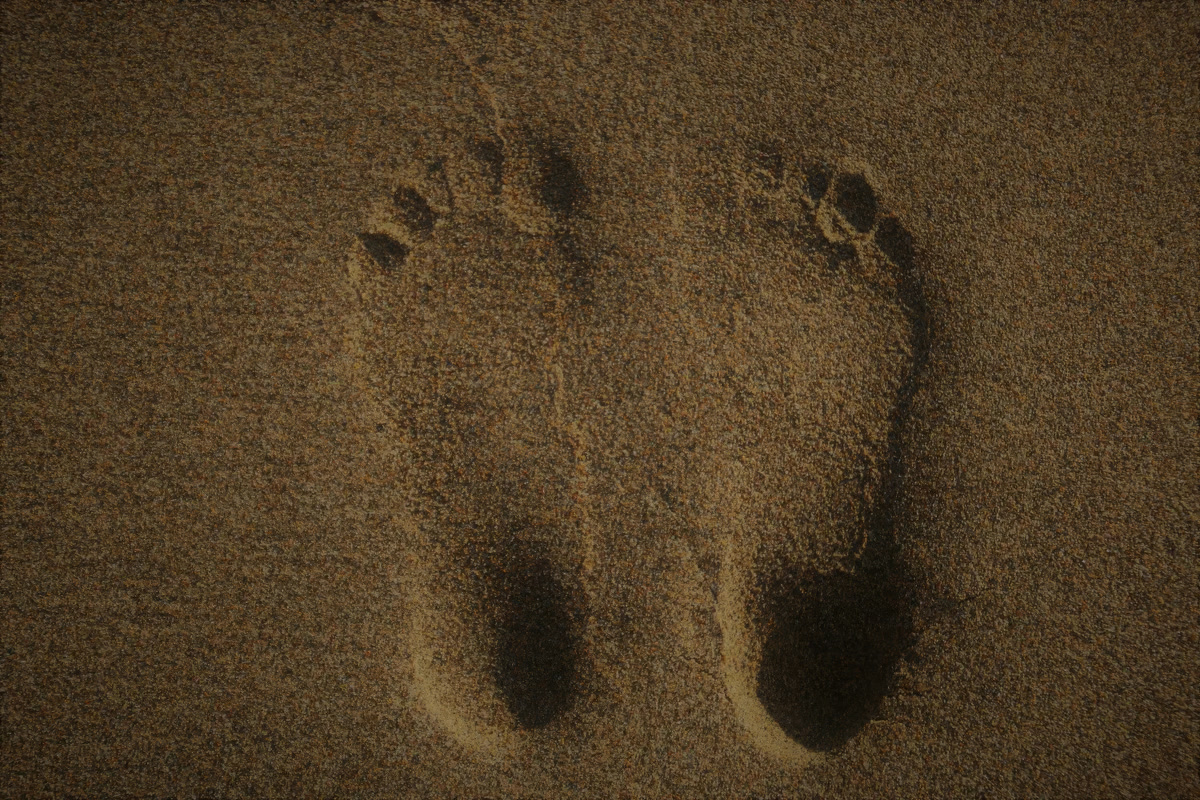 A pair of bare footprints pressed into sand