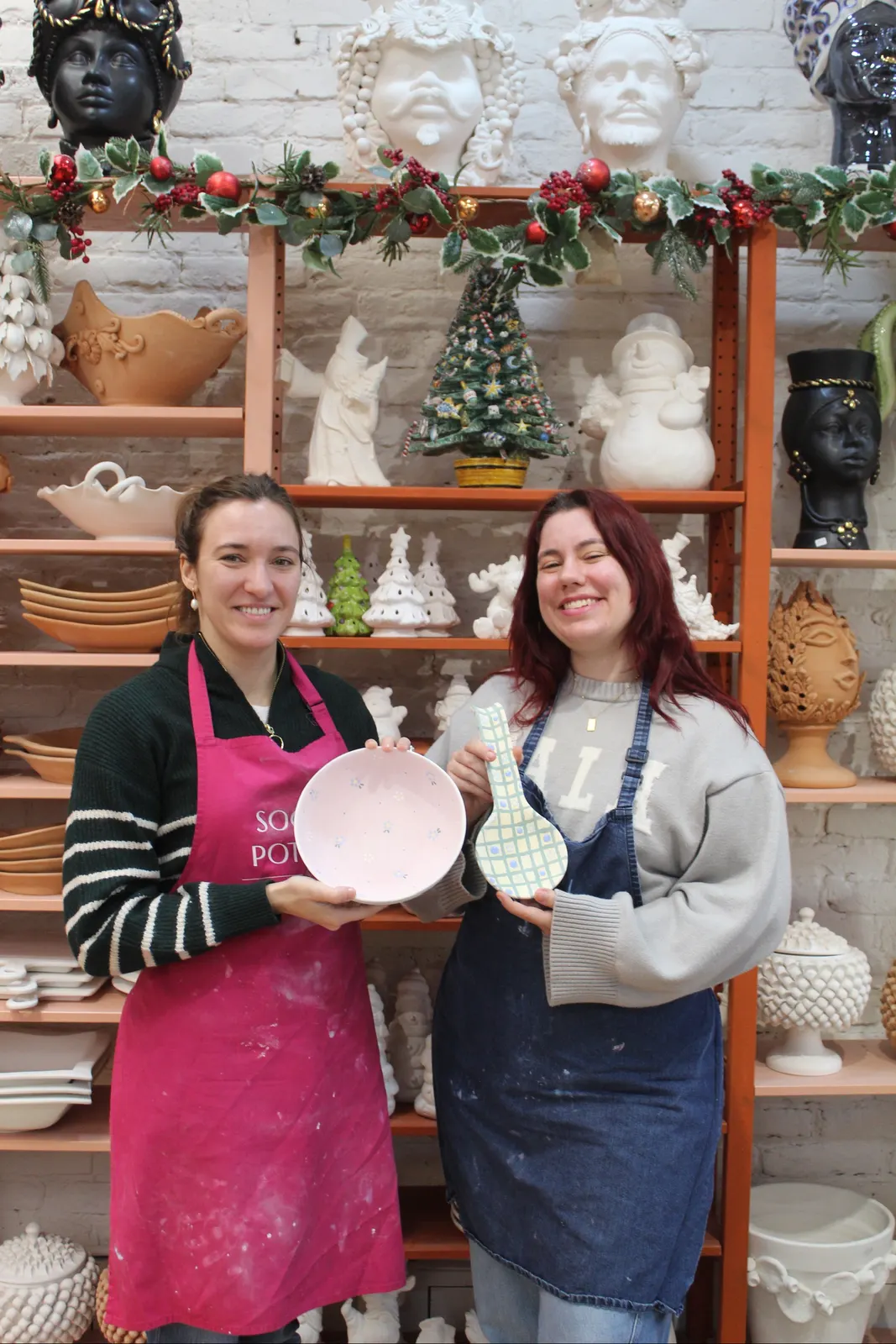 Two of the team with freshly painted pieces by the Christmas shelf