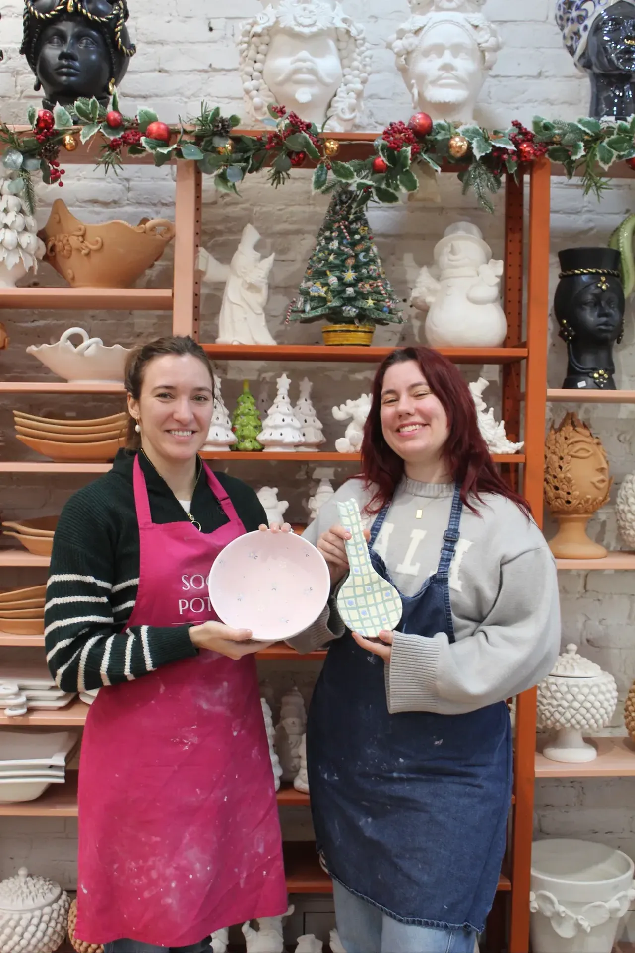 Two of the team with freshly painted pieces by the Christmas shelf