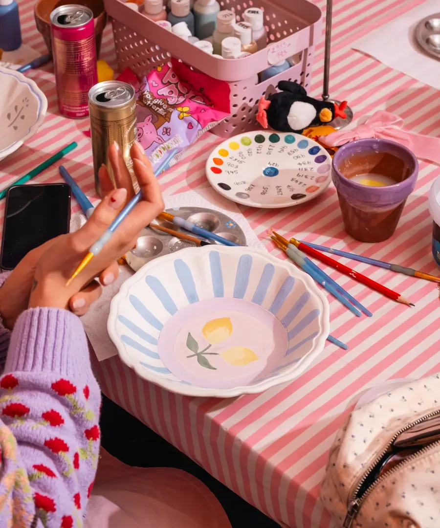 Two people painting ceramic pieces at a Social Pottery studio table in London