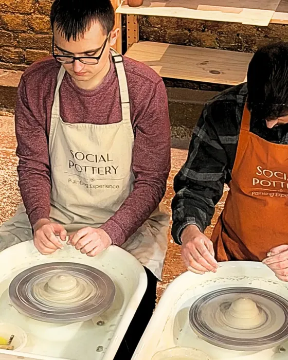 Two people centring clay on the pottery wheels at Social Pottery Studio 221 in Camden