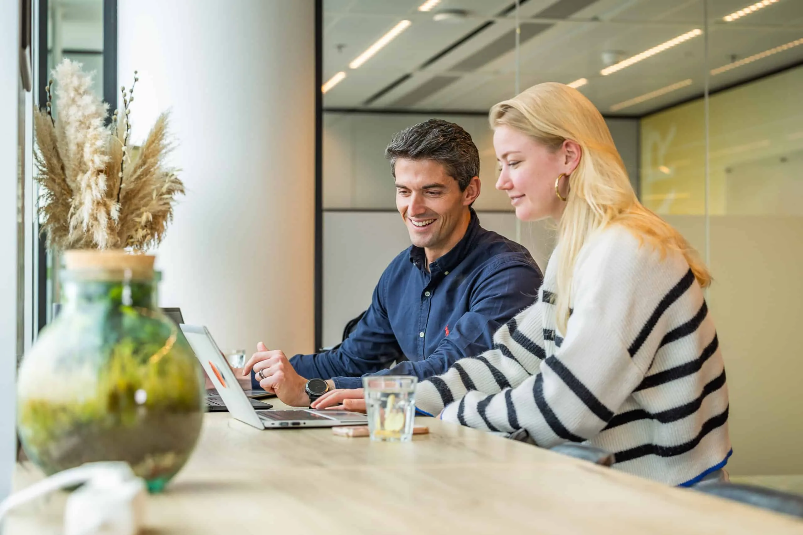 Two Ace colleagues working together on a laptop at the office bar